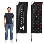A man wearing a navy blue t-shirt and jeans stands next to two custom black vertical flag banners on a white background. One banner features the white text 'MANDATED PROPERTY GROUP' with a white geometric logo, and the other shows a repeating pattern of small red, gray, and white logos.