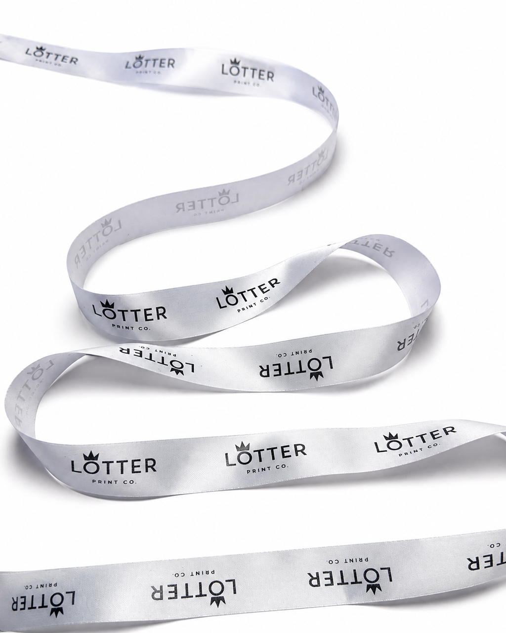 A white satin ribbon with a repeating black 'LOTTER PRINT CO.' logo pattern, coiled on a white background.
